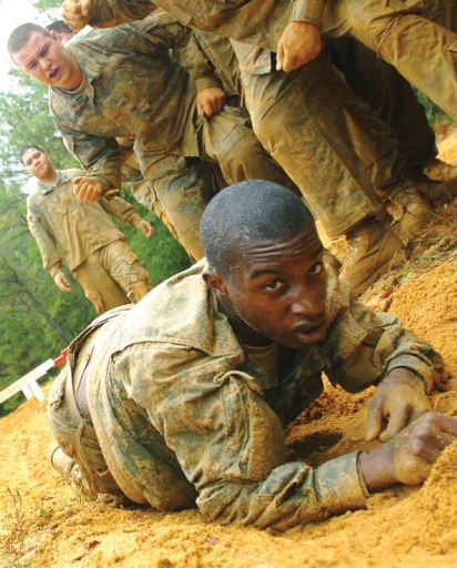 Cute black solider crawling in the sand during military boot camp